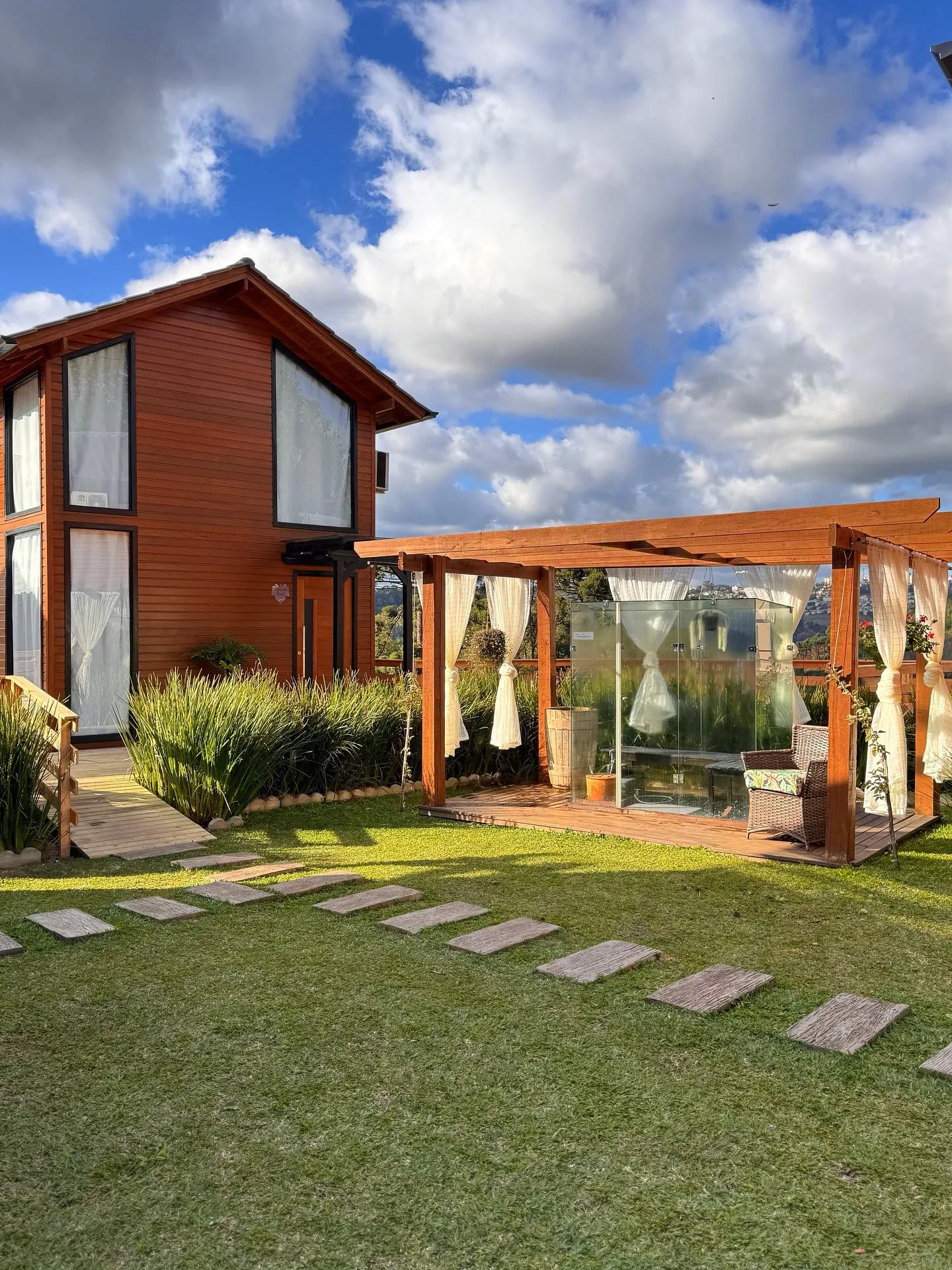 Cabana de madeira com pergolado e caminho de pedras no gramado